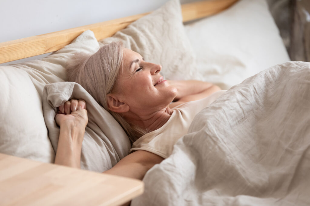 Satisfied middle-aged woman lying in bed